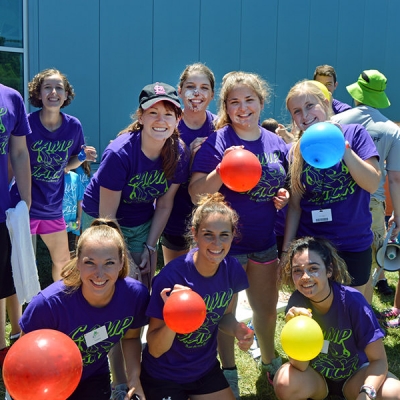 Camp staff poses for a photo holding colorful balloons