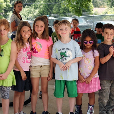 Young children wear colorful shirts to camp on a sunny day