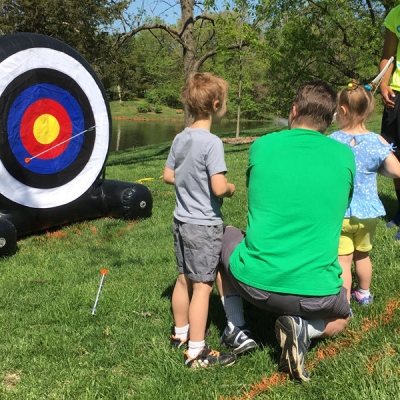 Father helps his children take aim at a child-size target.